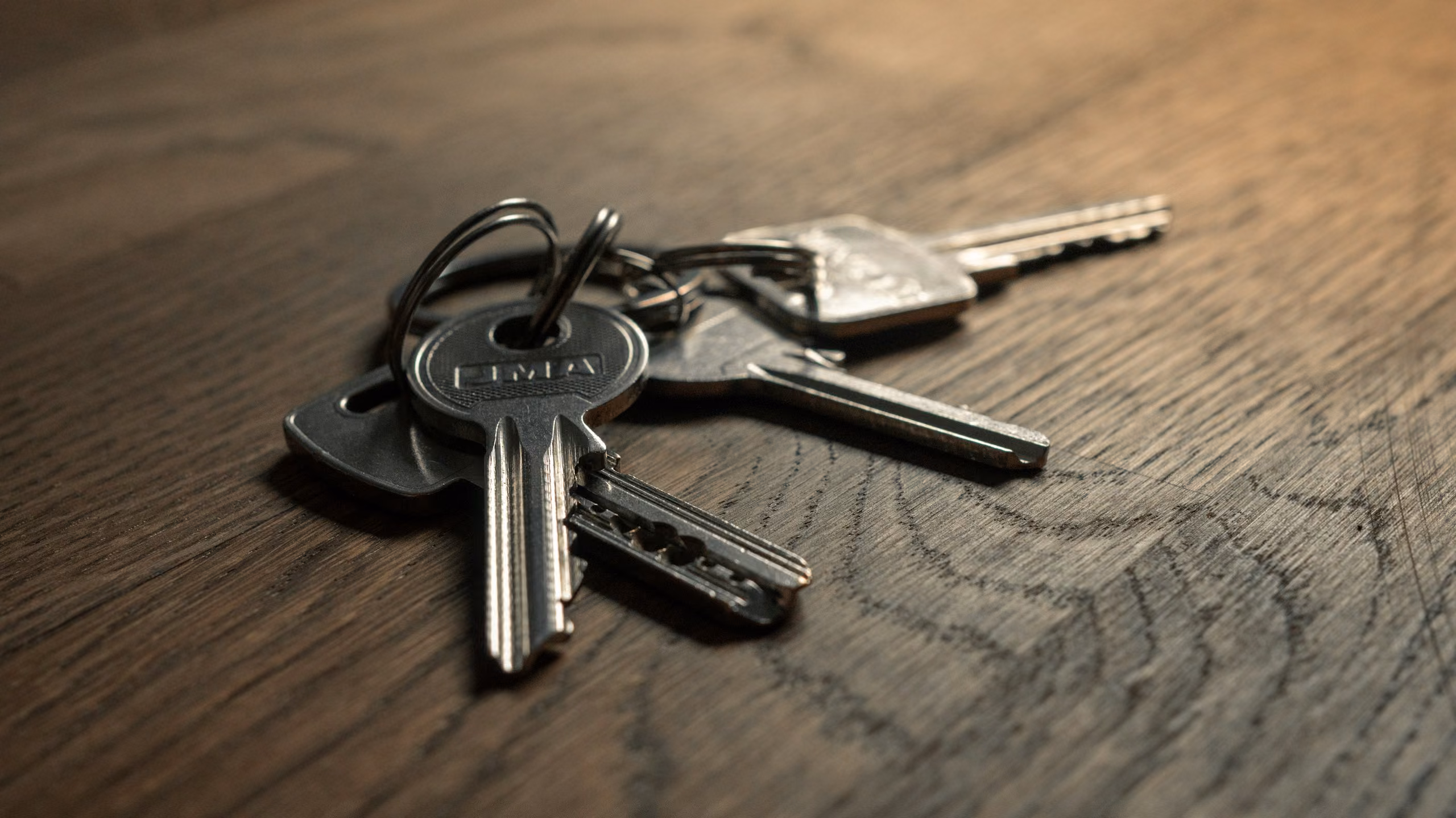 A ring of house keys lying on a dark wooden table