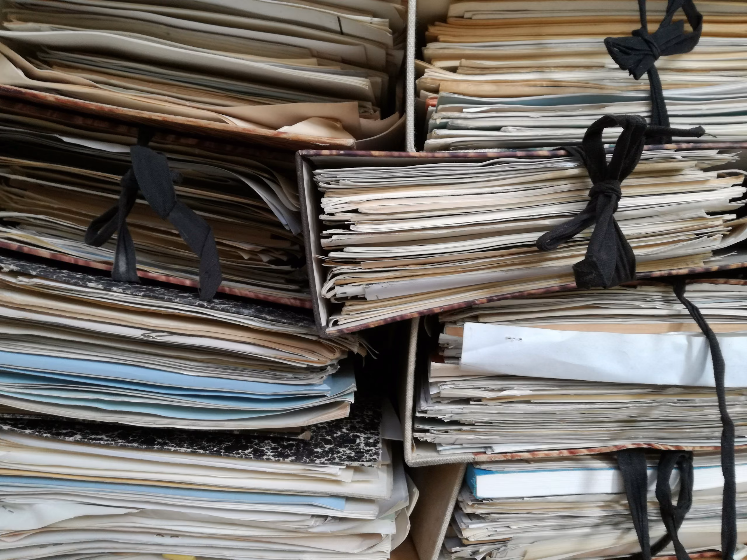 Bundles of archived case files tied with black ribbon, stacked on shelves